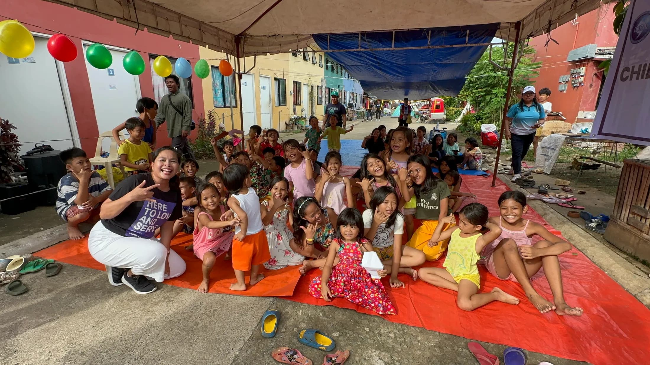 Children and adults gathered beneath a canopy