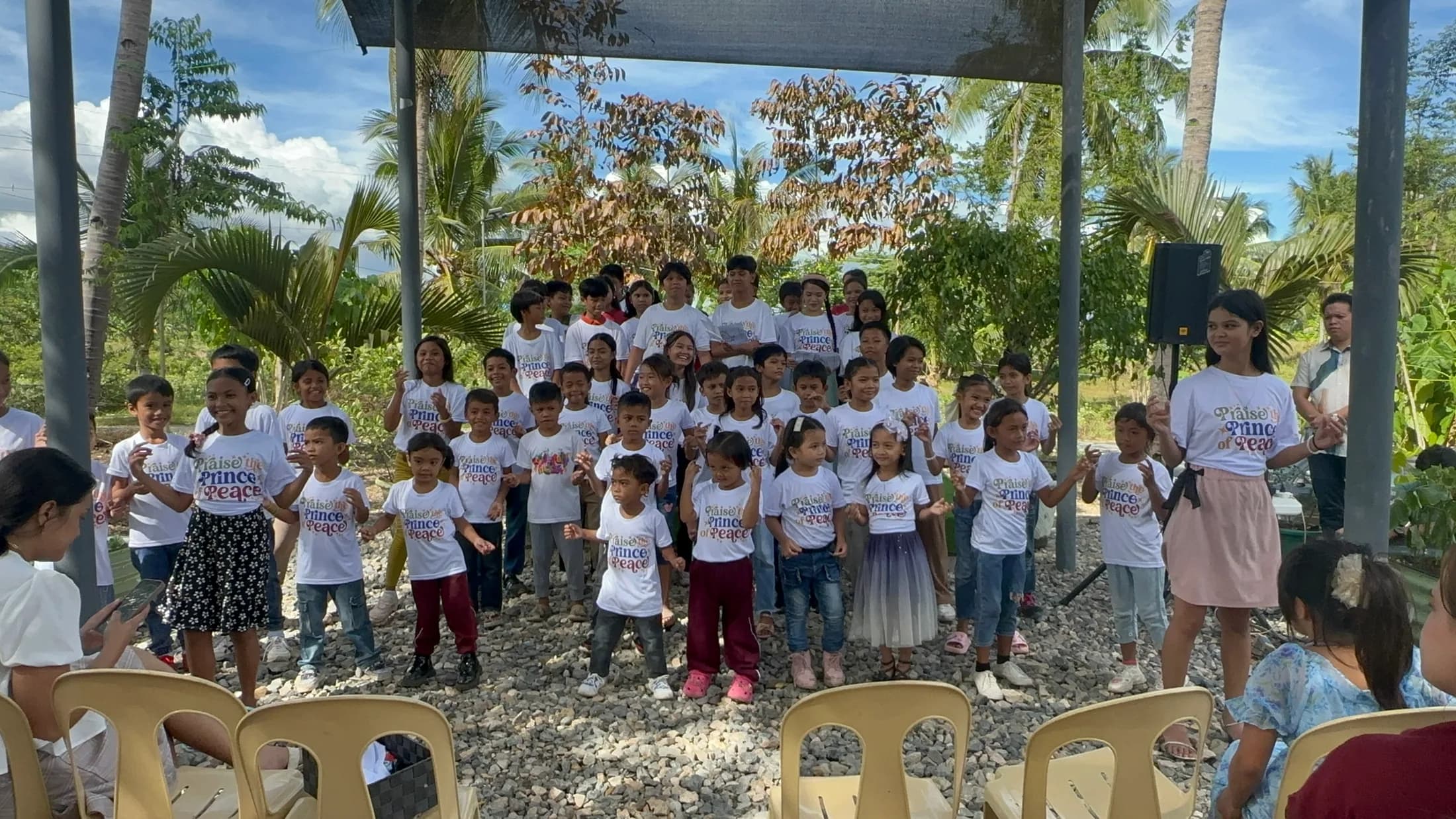 Children gathered outdoors with adults near a building