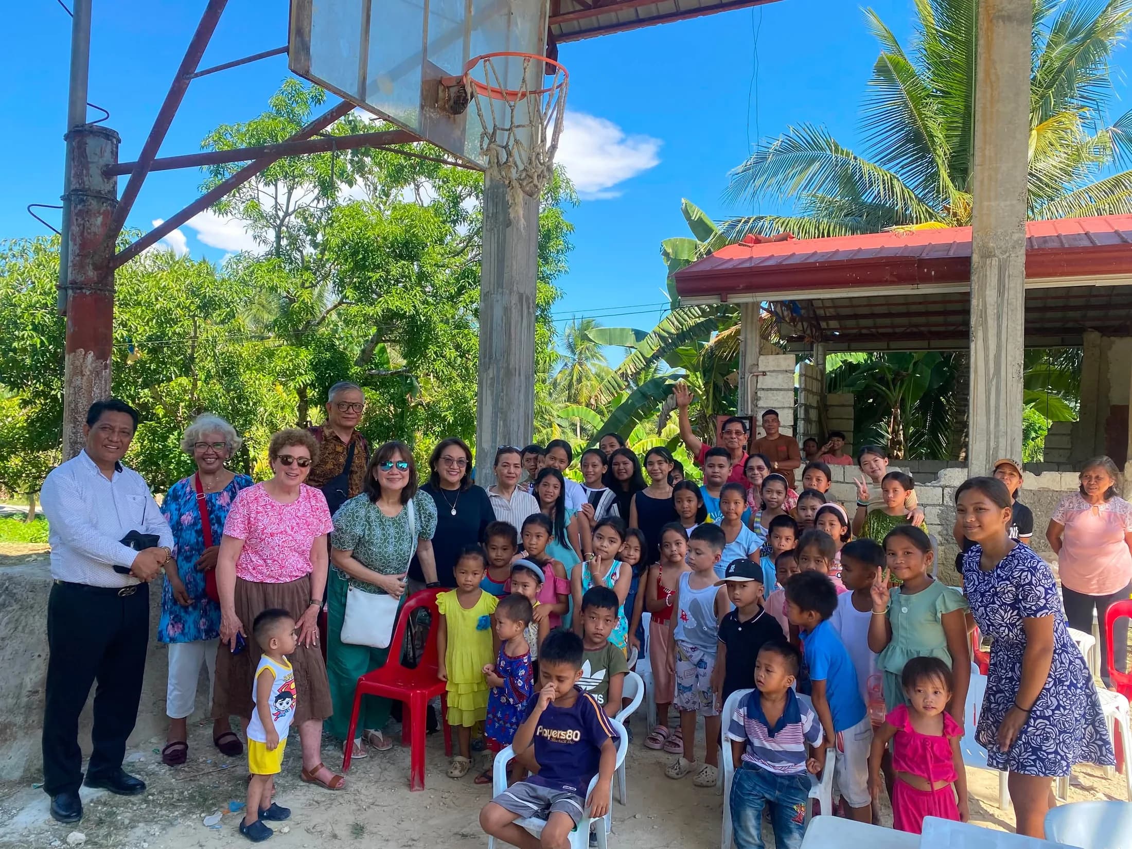 Children and adults posing together outdoors near a basketball hoop