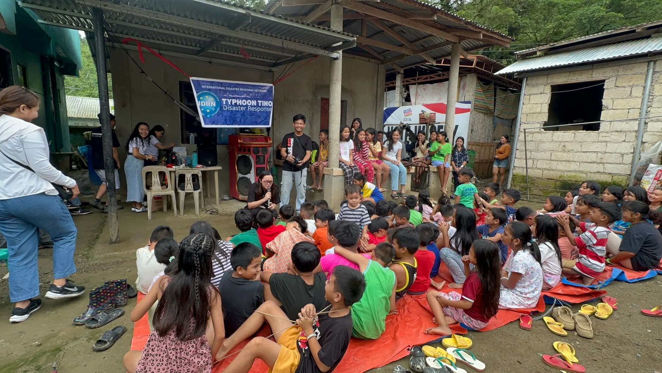 An adult speaking with children gathered outdoors