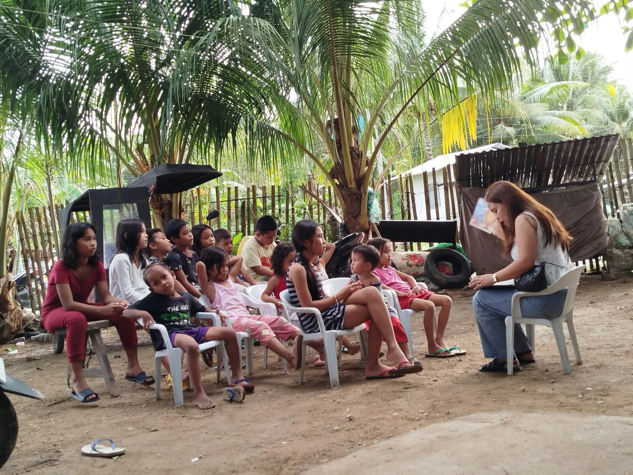 Children and adults seated together in an outdoor learning circle