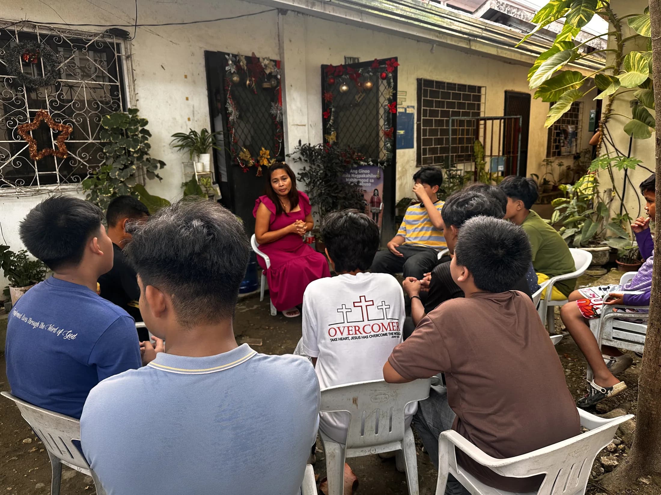 Children and adults seated in a small group outside a home