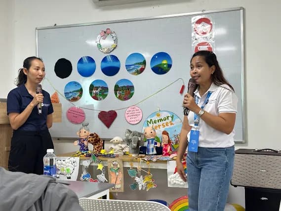 Two women speaking beside a display of learning materials