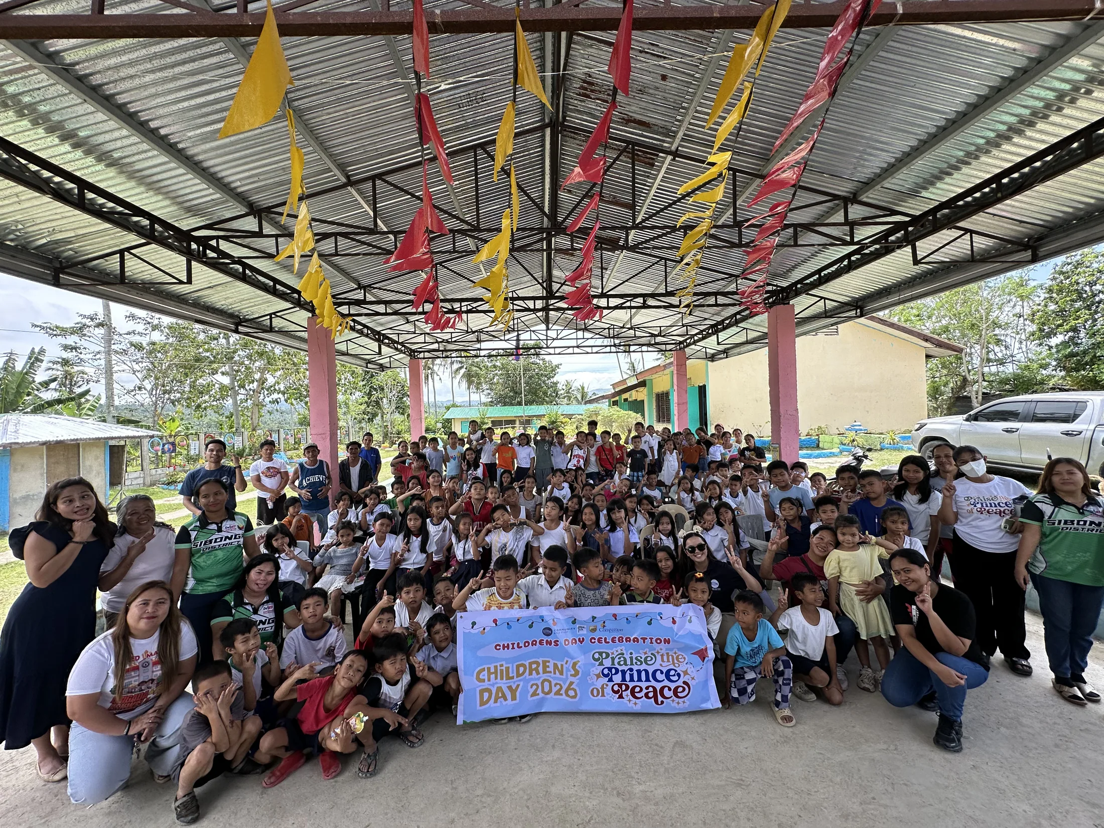 Children and adults gathered beneath a covered court