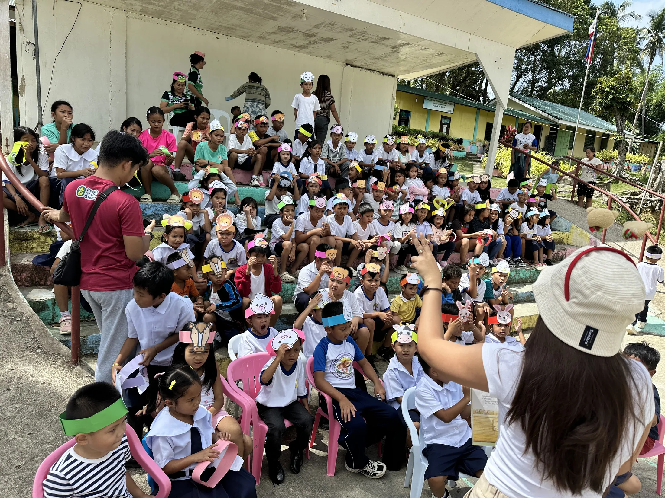 Children gathered outdoors wearing colorful animal headbands