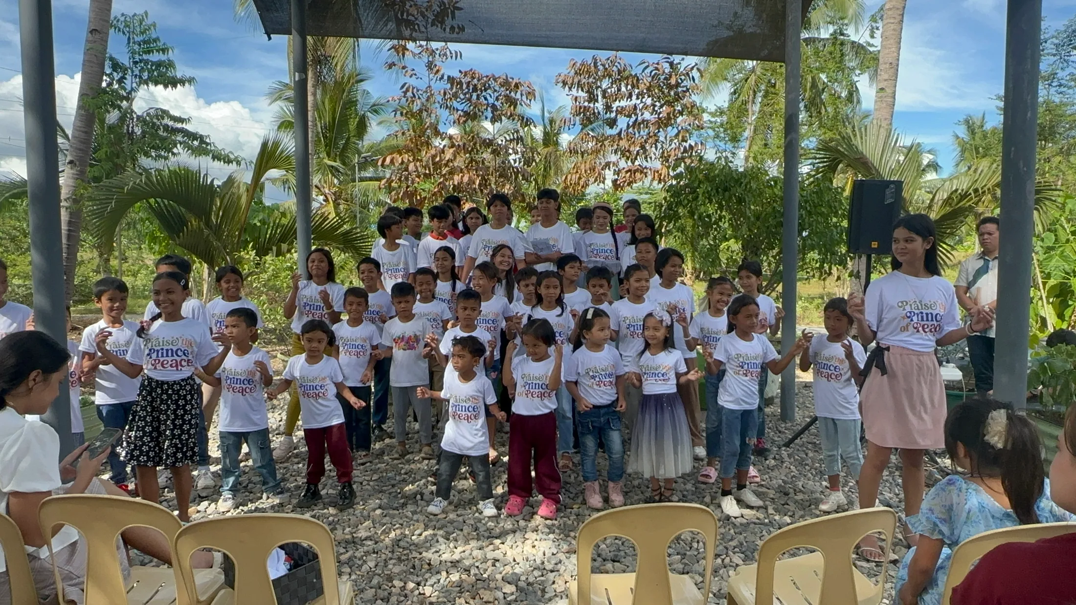 Children gathered outdoors with adults near a building